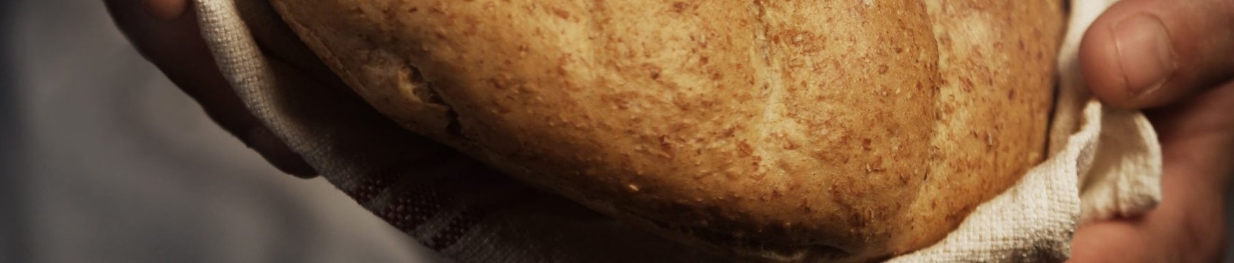 Un boulanger du Panetier tient un pain de campagne dans un linge